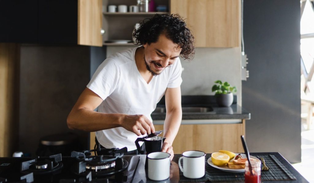 Hispanic young man preparing coffee for breakfast in kitchen at home in Mexico Latin America